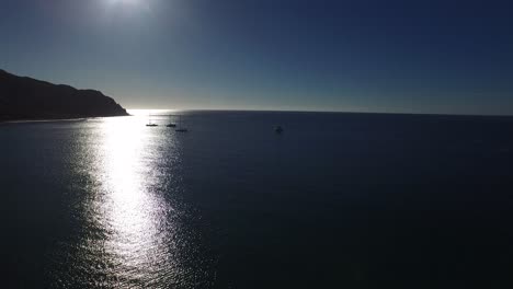 Aerial-shot-of-sail-boats-with-sun-backlight,-Cabo-Pulmo-National-Park,-Baja-California-Sur