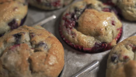 Slow-pan-left-freshly-baked-blueberry-and-cranberry-muffins-in-colorful-wrappers-up-close