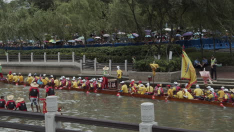 Chinese-people-dressed-in-yellow-t-shirts-paddle-and-hit-drums-on-a-dragon-boat-during-dragon-boat-festival-in-Guangzhou,-Guangdong,-China