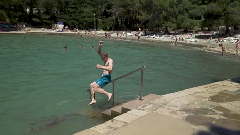 Blond-young-athletic-European-man-sliding-a-handrail-oriented-into-a-sea,-speed-ramp,-slow-motion