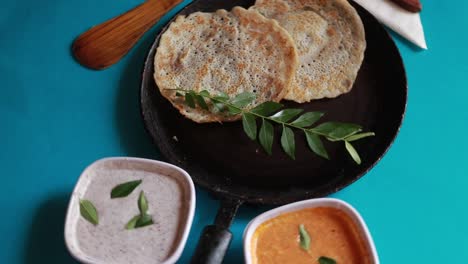 Rotierendes-Südindisches-Essensset-Dosa-Mit-Curry-Und-Chutney-Auf-Blauem-Hintergrund