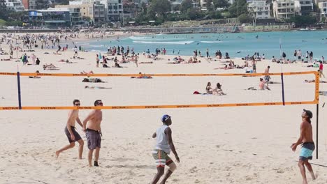 Eine-Gruppe-Von-Vier-Freunden-Spielt-An-Einem-Frühlingstag-Am-Bondi-Beach-In-Sydney,-Australien,-Eine-Partie-Beachvolleyball
