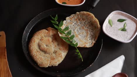 Rotierendes-Südindisches-Essensset-Dosa-Mit-Curry-Und-Chutney-Auf-Schwarzem-Hintergrund