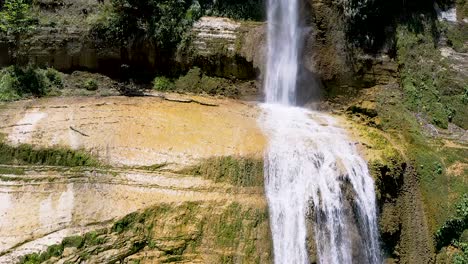 Langsame-Luftaufnahme-Eines-Großen-Tropischen-Wasserfalls,-Der-In-Ein-Wasserbecken-Darunter-Stürzt,-Wo-Einheimische-Touristen-Entspannen-Und-Ihren-Tropischen-Urlaub-Genießen