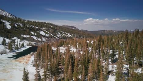 Aerial-flight-over-a-winter-forest-next-to-a-frozen-lake-in-the-Mammoth-Lake-mountain-range