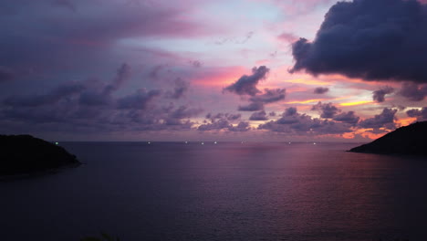 Weitwinkel-Panorama-Zeitrafferaufnahme-Eines-Tropischen-Sonnenuntergangs-Nach-Einem-Regnerischen-Monsuntag-Mit-Goldenem,-Violettem-Und-Blauem,-Dramatischem-Himmel-Und-Wolkenlandschaft-über-Einer-Ruhigen,-Erhöhten-Meeresbucht-Mit-Blick