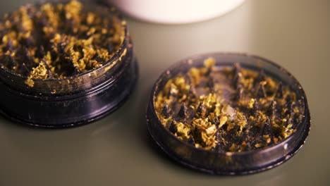 Panning-close-up-of-cannabis-grinds-in-a-plastic-grey-grinder-in-60-fps