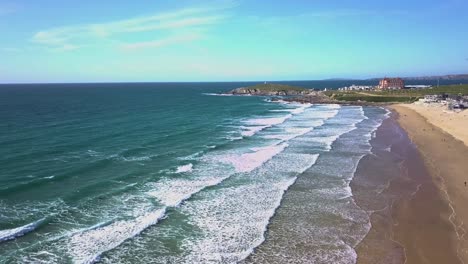 Wide-drone-shot-of-surfers-waiting-on-waves-as-they-break-onto-Fistral-beach