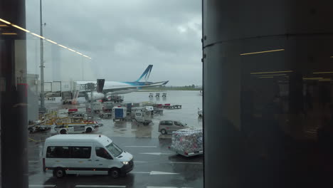 Left-Dolly-Truck-on-planes-and-vehicles-at-work-on-the-pavement-Tarmac-at-Paris-Orly-airport-before-takeoff,-view-from-boarding-zone