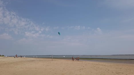 Family-with-children-on-holiday-playing-with-a-blue-kite-fly-on-the-beach-of-Gatseau-in-Oleron