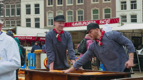 Dos-Hombres-Holandeses-Con-Ropa-Tradicional-Cargando-Queso-Redondo-En-Carro