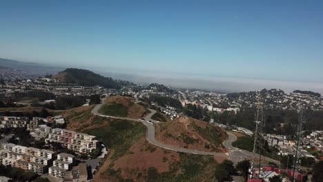 twin-peaks-mountains-san-francisco-aerial-shot-fog-network-towers-pan-left-moon-in-daylight
