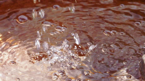 Footage-of-two-steams-of-water-hitting-the-surface-and-causing-splashes,-bubbles-and-drops