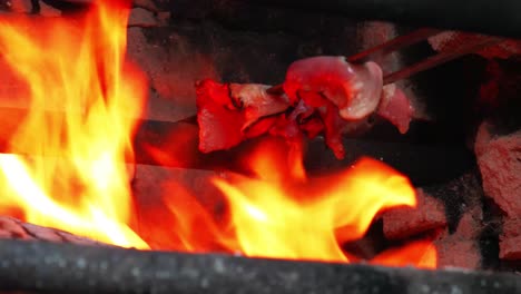 Bacon-being-cookend-on-outdoors-barbecue-with-huge-yellow-red-flame-and-heat-while-grease-are-going-down-to-the-flame