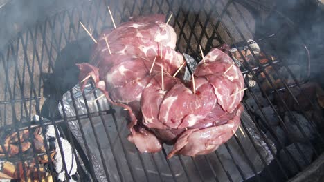 Slow-pan-of-game-meat-wrapped-in-bacon-secured-with-toothpicks-on-the-barbecue