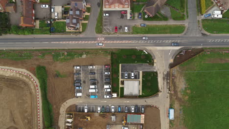 Stabilized-top-down-aerial-view-of-traffic-passing-by-the-Redrow-Homes-new-build-estate-names-'The-Hoplands