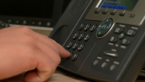 A-close-up-of-a-hand-picking-up-and-dialing-an-office-phone-then-hanging-up-in-slow-motion