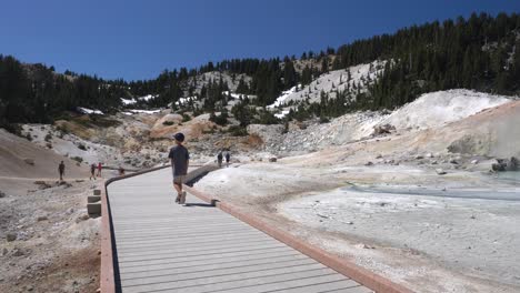 4K-video-of-boy-walking-on-the-boardwalk-trail-of-Bumpass-Hell-in-Lassen-Volcanic-National-Park,-California---July-28,-2019