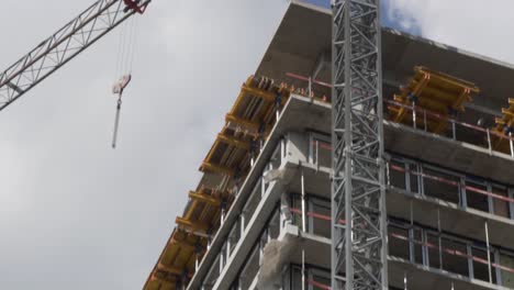 Tilt-down-shot-of-a-high-building-under-works-with-a-crane