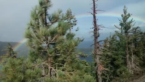 A-colorful-and-bright-rainbow-lighting-up-a-dark-grey-sky-on-the-way-to-Emerald-Bay-State-Park-in-Lake-Tahoe,-California