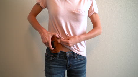 Slow-motion-of-a-woman-placing-a-holstered-handgun-in-her-waistband-to-conceal-it
