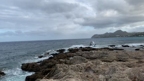 Sailing-boat-yacht-wrecked-on-the-rocks-and-sinks-in-the-mediterranean-sea-in-Mallorca-on-a-cloudy-day-in-summer