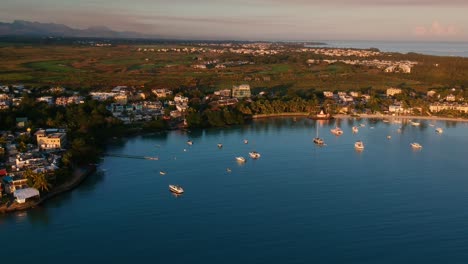 Aerial-panoramic-of-Grand-Bay,-with-boats-anchored,-houses,-green-land-an-the-ocean-and-mountains-in-the-background