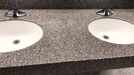 Bathroom-granite-countertop-with-two-oval-white-under-mount-sinks-with-faucet-and-tiled-walls-and-floors-around
