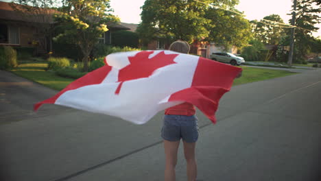 Mädchen-Reitet-Auf-Einem-Longboard-Und-Schwenkt-Zur-Goldenen-Stunde-Eine-Kanadische-Flagge-Hinter-Sich