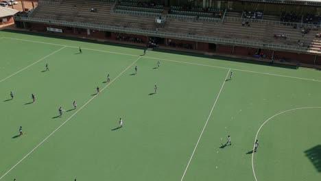 A-diagonal-pan-left-drone-shot-of-a-field-hockey-game-under-sunny-conditions