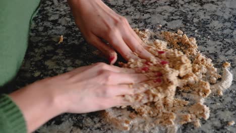 Woman-hands-kneading-pieces-of-dough-on-floured-countertop-to-join-it-together