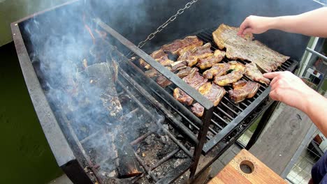 slow-motion-of-white-man-on-a-black-grill-cooking-roasted-meat-on-a-sunny-day