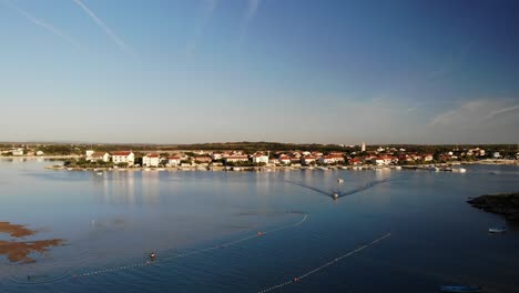Panorama-Aéreo-De-Una-Ciudad-Nin-Con-Laguna-Y-Barco-Acercándose-Al-Atardecer