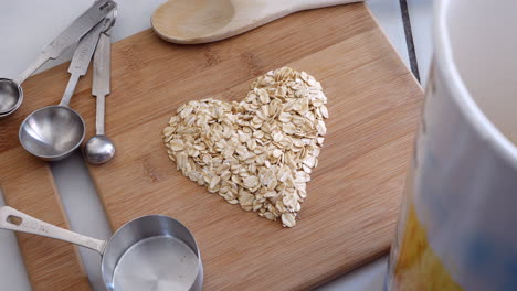 A-pile-of-oat-grain-cereal-in-a-heart-shape-with-kitchen-utensils-for-a-healthy-oatmeal-breakfast-TOP-DOWN