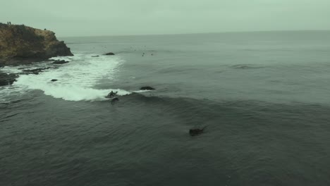 Aerial-of-Surfer-Riding-a-Wave-dodging-rocks-on-a-Cold-day-at-Pichilemu,-Chile-4K