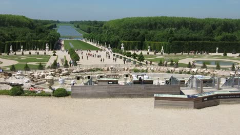 Nice-view-over-the-gardens-of-the-Versailles-Palace,-with-a-big-green-forest-and-a-lake-on-the-background