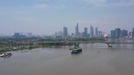 Aerial-slow-push-in-on-freighter-transporting-shipping-containers-on-the-Saigon-river-on-a-sunny-clear-day