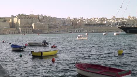 A-small-Gondola-boat-arrives-at-the-harbour-from-Valletta,-Malta-in-bg