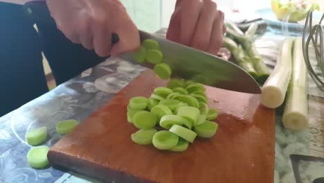 Closeup-footage-of-home-kitchen-table-with-woman-slicing-onions-on-the-wooden-cutting-board