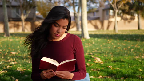 A-young-woman-school-girl-studying-and-reading-a-book-on-a-campus-lawn-or-outdoor-park-SLOW-MOTION