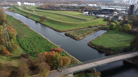 Descending-aerial-shot-of,-river-and-walking-path-beside-chemical-area