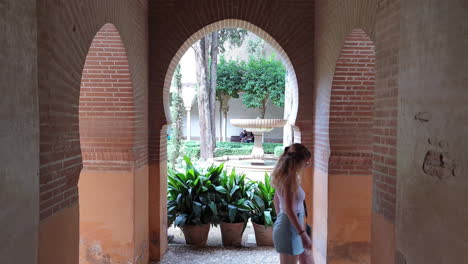 Woman-under-arcades-at-Court-of-Lindaraja-in-Alhambra,-Granada,-Spain