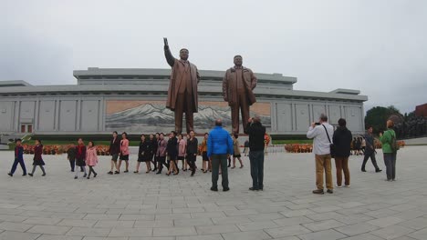 Tourists-take-photos-of-Mansudae-Grand-Monument-as-local-women-walk-past