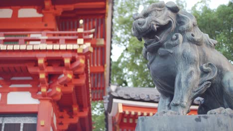 Stone-lion-statue-panning-to-a-beautiful-tall-shrine-early-morning-in-Kyoto,-Japan-soft-lighting-slow-motion-4K