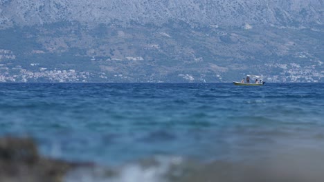 Distant-stationary-small-boat-in-wide-open-sea-of-Croatia,-low-angle-shot