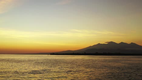 Romantisches-Luftpanorama,-Kleine-Insel-Im-Offenen-Ozean-Mit-Bergen-Im-Wunderschönen-Goldenen-Licht-Des-Sonnenuntergangs