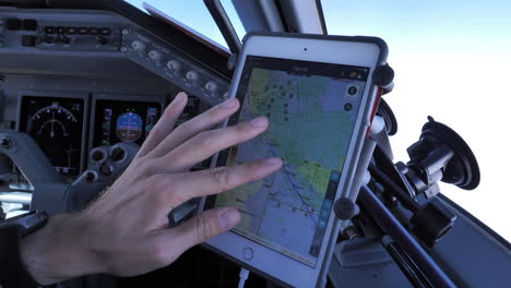 Ein-Pilot-überprüft-Die-Route-Des-Flugzeugs-Auf-Einem-Tablet,-Das-Am-Cockpitfenster-Befestigt-Ist