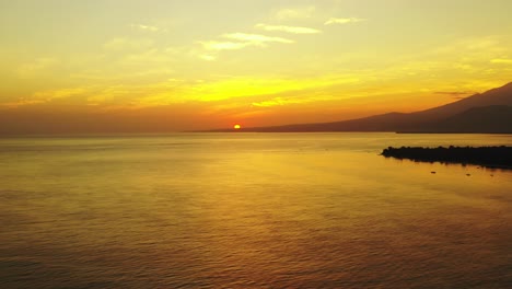 Romantische-Meereslandschaft-Aus-Der-Luft,-Kleine-Insel-Im-Offenen-Ozean-Mit-Bergen-Im-Wunderschönen-Goldenen-Licht-Des-Sonnenuntergangs