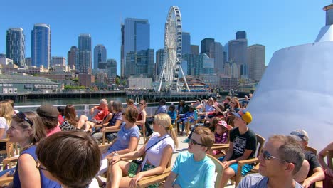 Touristen-Genießen-Eine-Fahrt-Mit-Dem-Wassertaxi-Mit-Riesenrad-Und-Den-Sehenswürdigkeiten-Von-Seattle-Im-Hintergrund