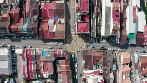 The-intersection-of-Chulia-and-Beach-streets-in-George-Town,-Penang-Island-Malaysia-seen-from-above-with-vehicle-traffic,-Aerial-top-view-lowering-shot